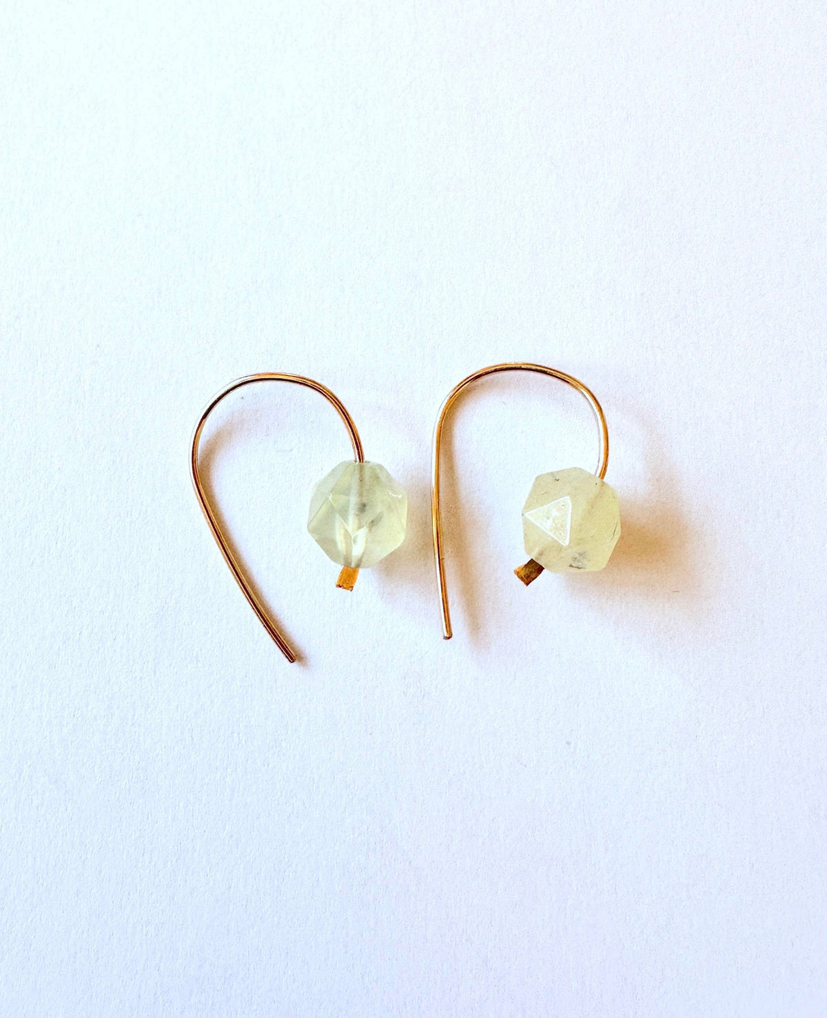 Pair of gold earrings with clear gemstones on a white background